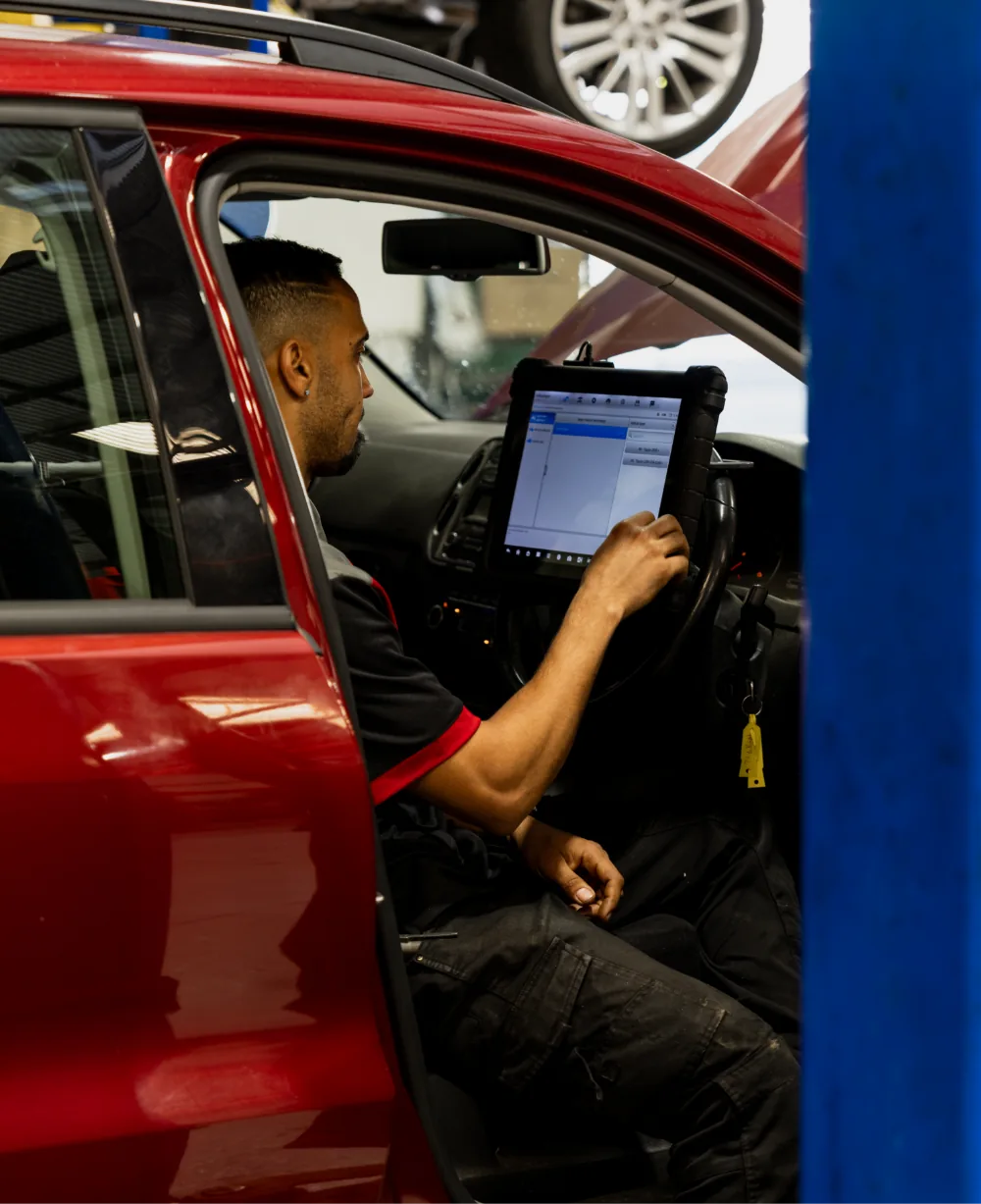 Technician performing European car diagnostics using computer tablet at Brisbane workshop
