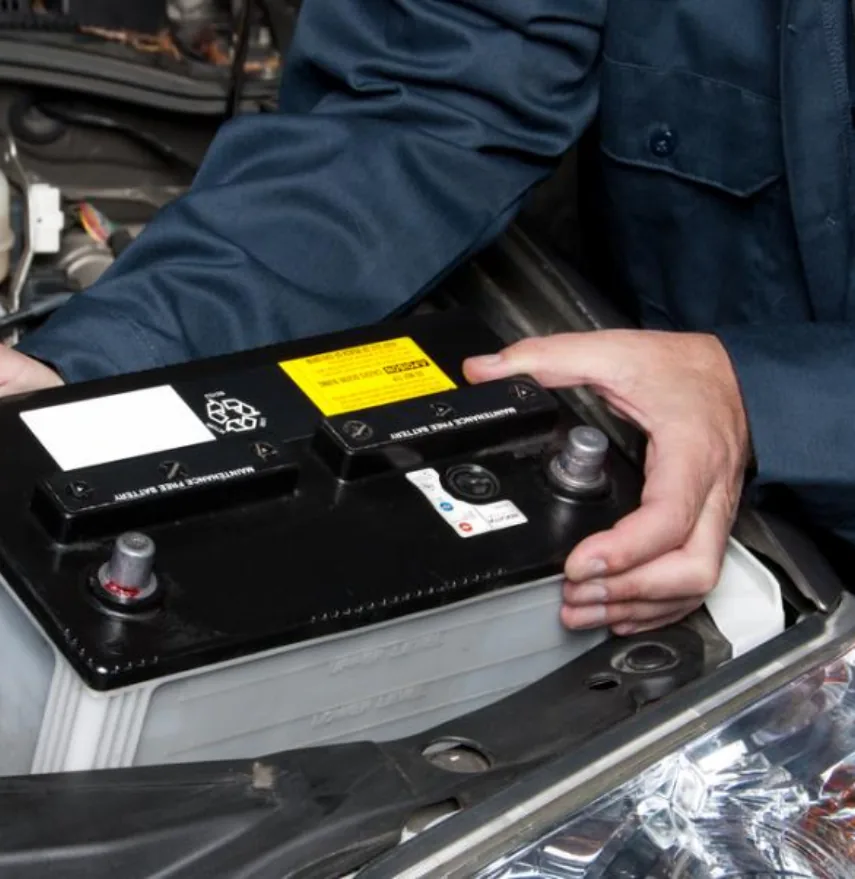 Mechanic installing new car battery in European vehicle engine bay