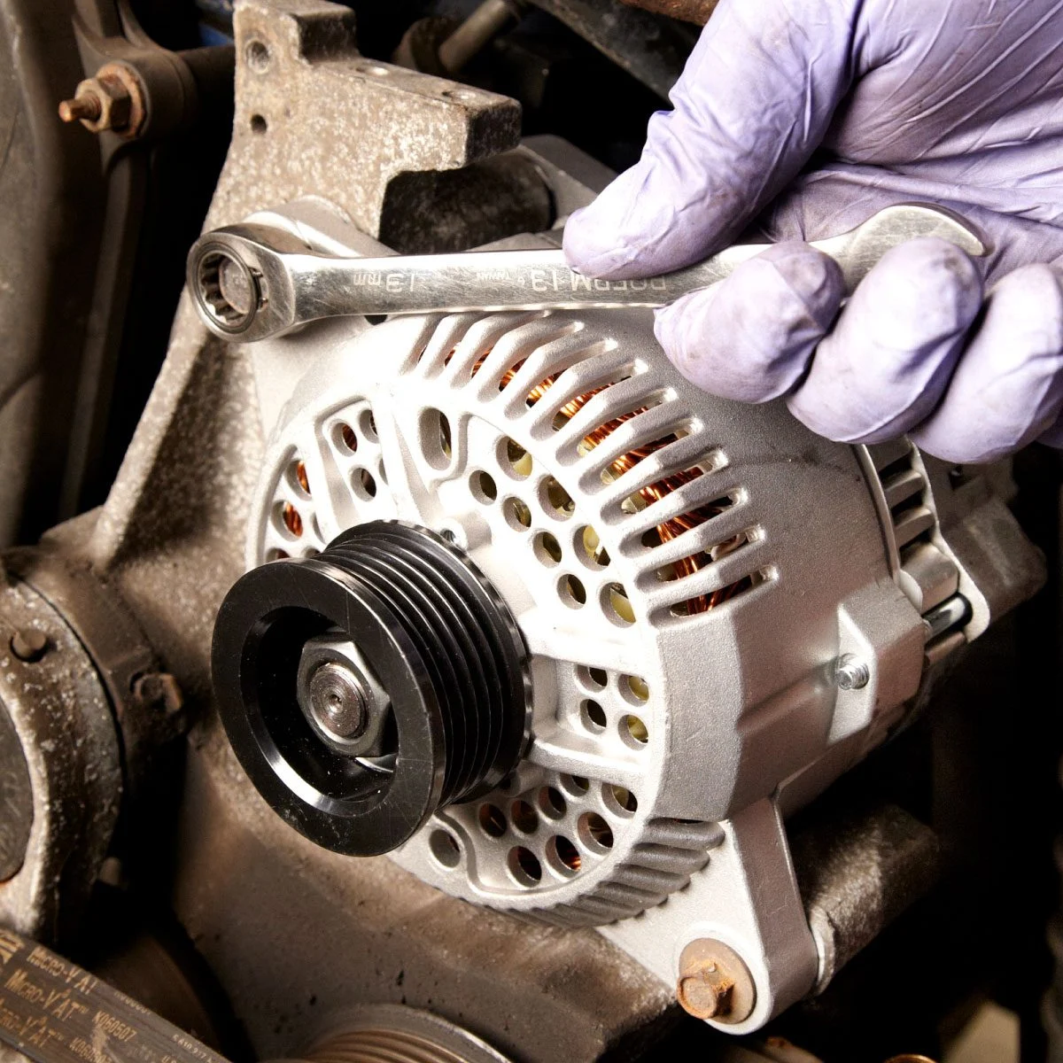 Mechanic replacing car alternator during European vehicle service repair in Brisbane
